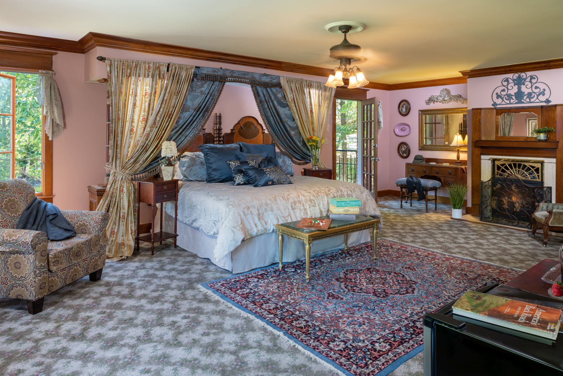 Luxurious bedroom with canopied king bed, Oriental area rug, fireplace, and comfy upholstered armchair.