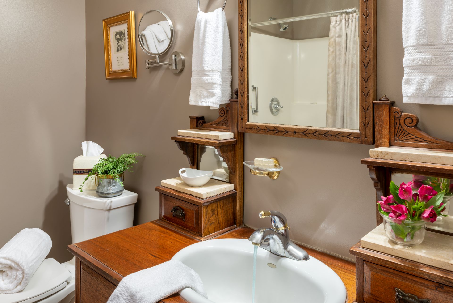 Bathroom with antique vanity with mirror, toilet, and plush white towels hanging nearby.