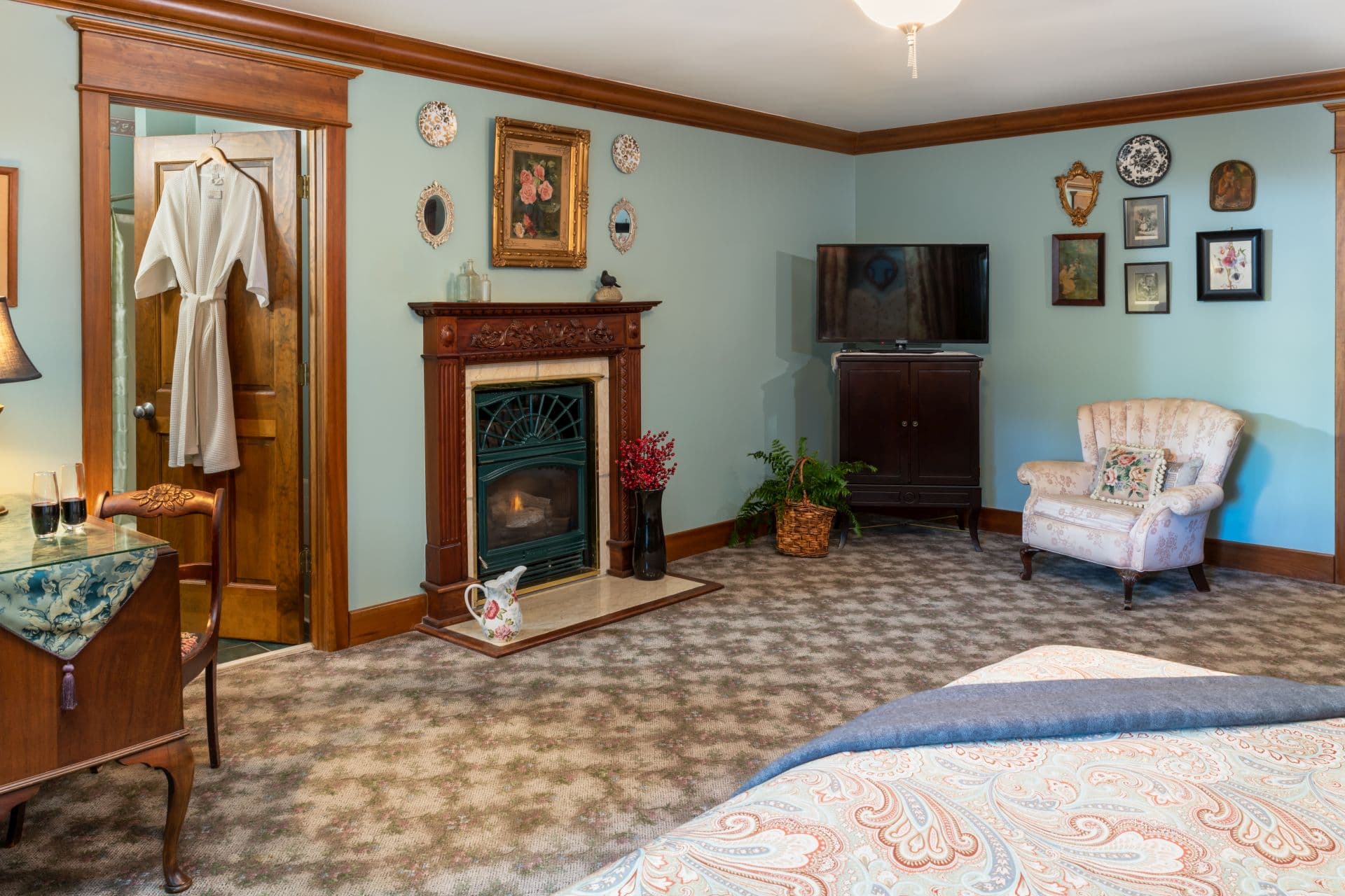 Spacious bedroom with fireplace, flat-screen TV, cozy armchair, and oak furniture & woodwork.