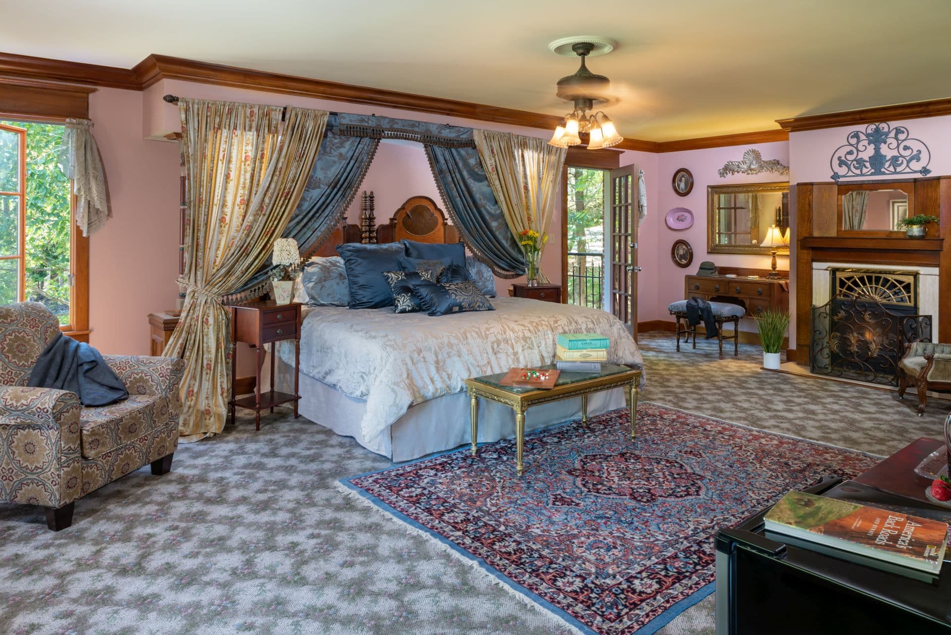 Luxurious bedroom with canopied king bed, Oriental area rug, fireplace, and comfy upholstered armchair.