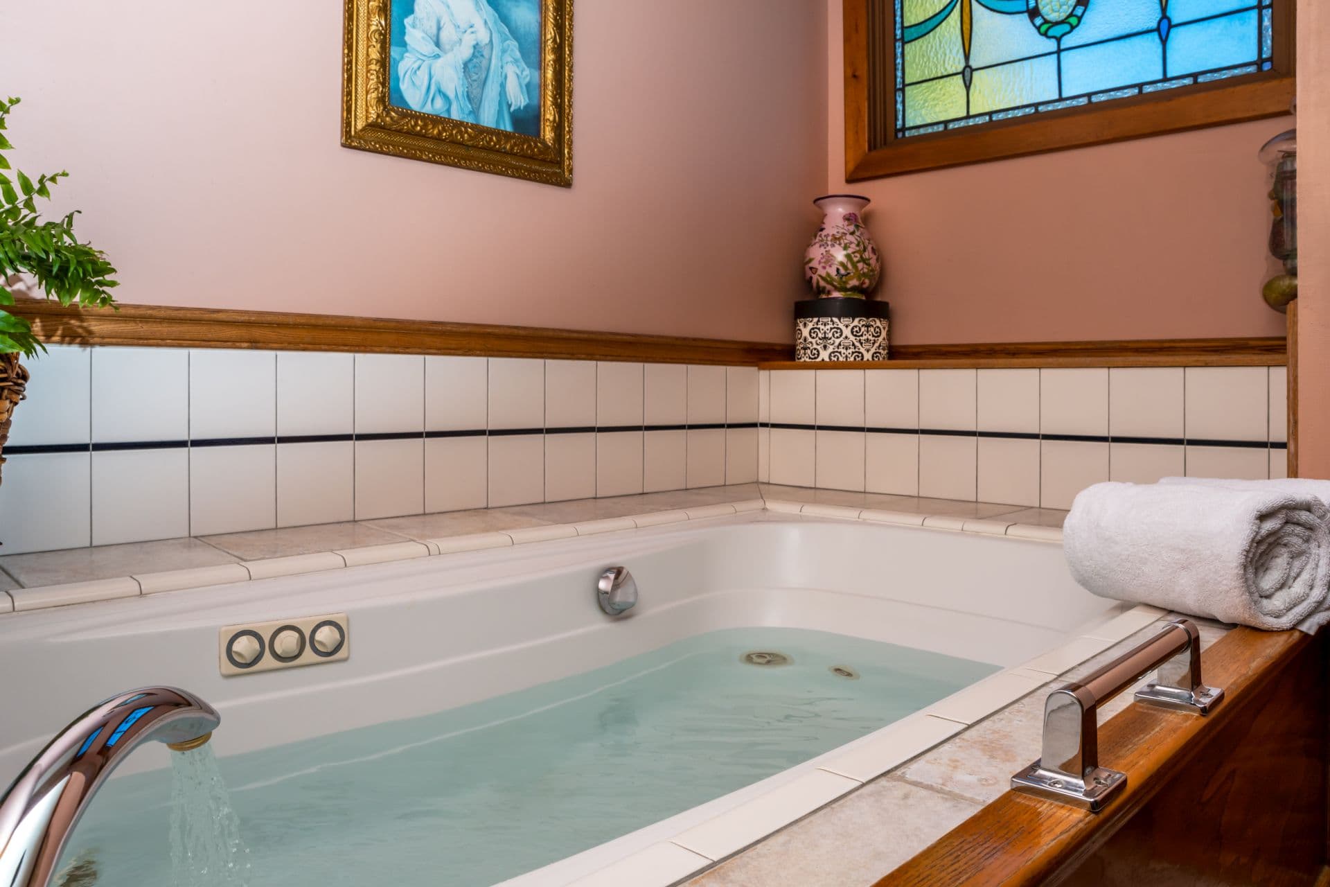 Soaking Jacuzzi tub softly lit by sunlight coming through a stained glass window.