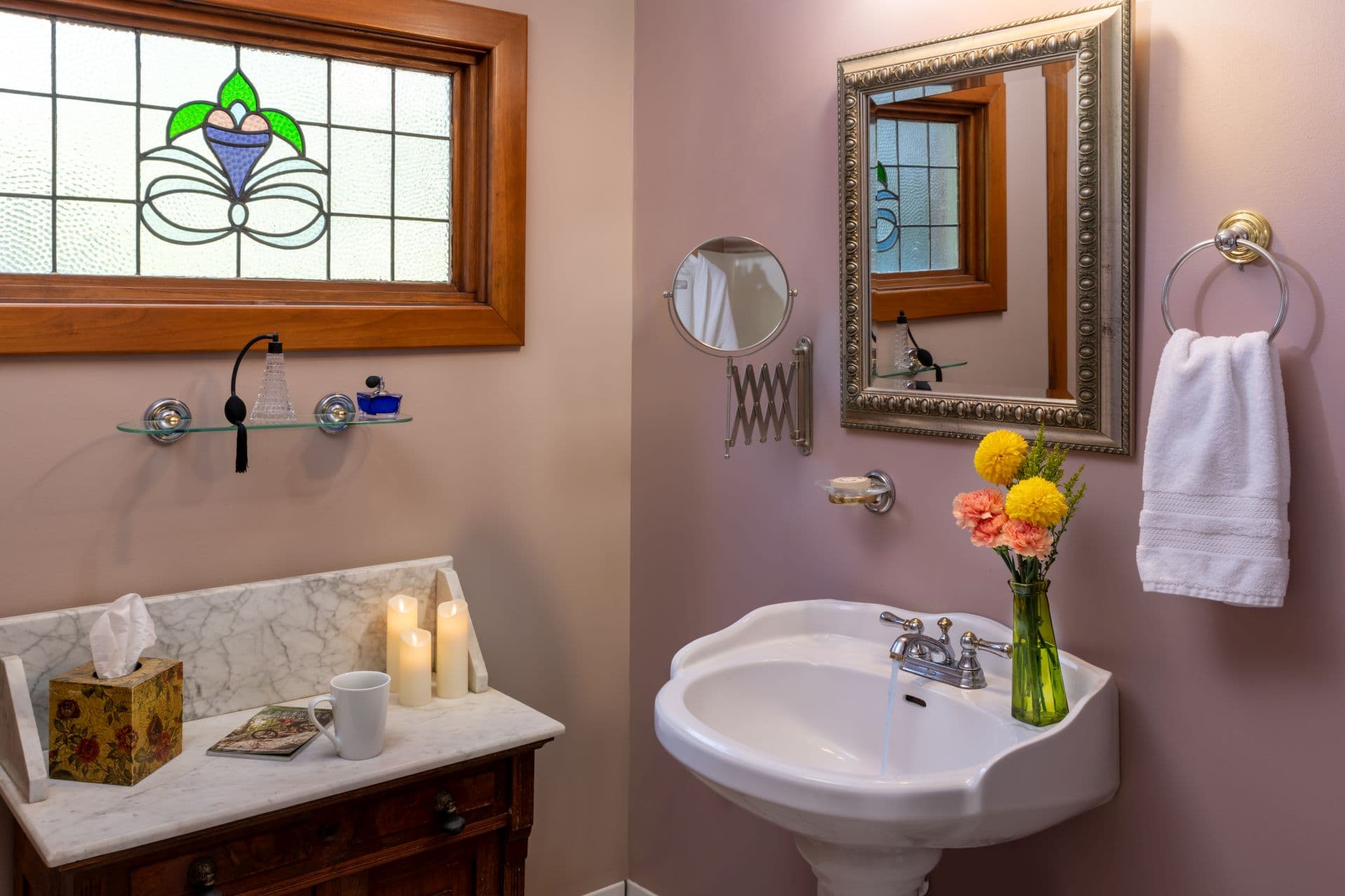 Charming bathroom with pedestal sink, antique dry sink, and stained glass window.