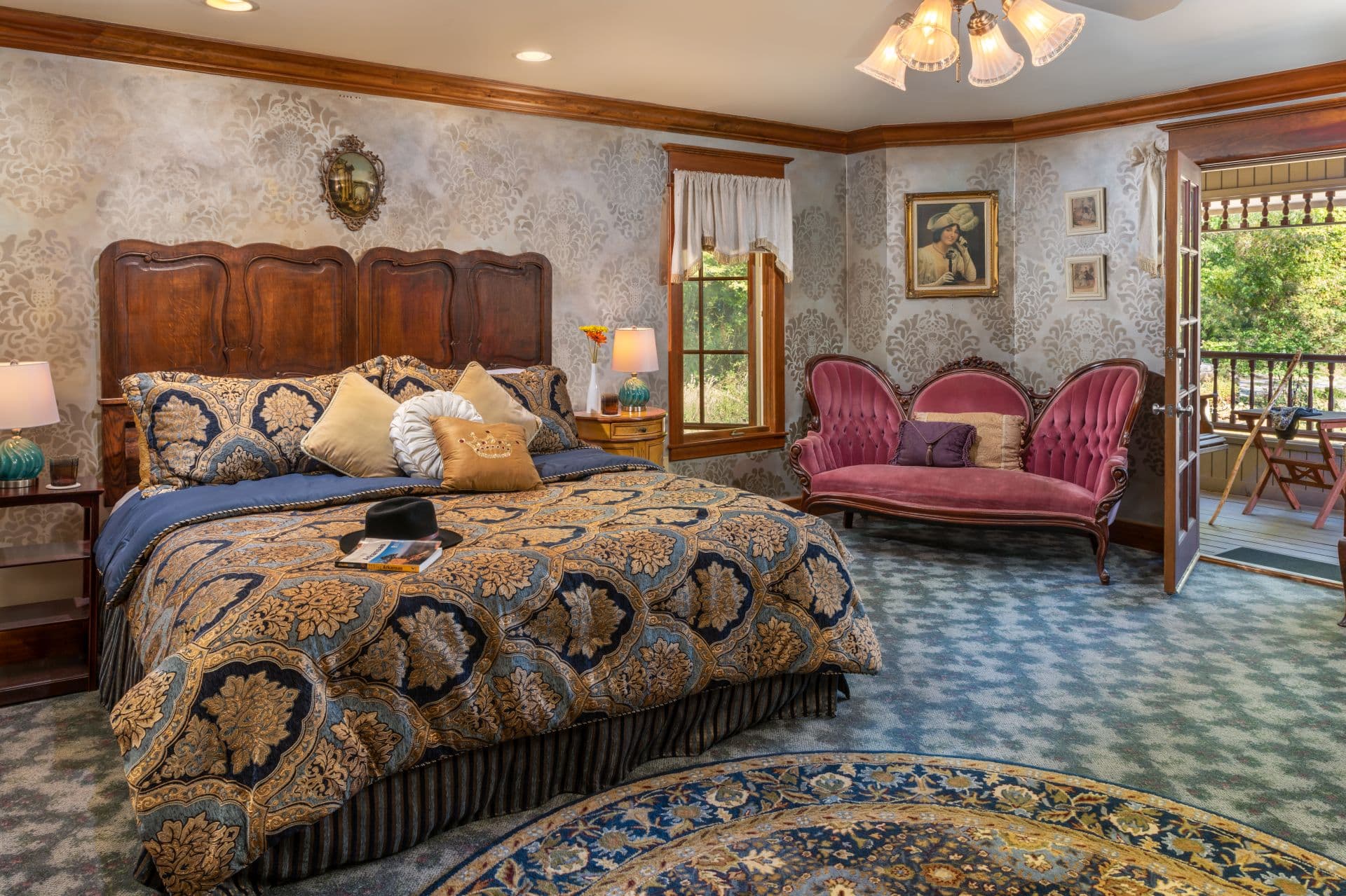 Elegant bedroom with king bed, antique velvet sofa, and doorway to private balcony.