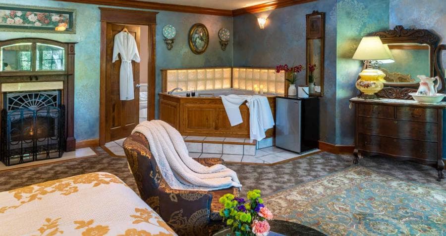 A cozy bedroom featuring a fireplace, a large tub, and elegant furnishings.