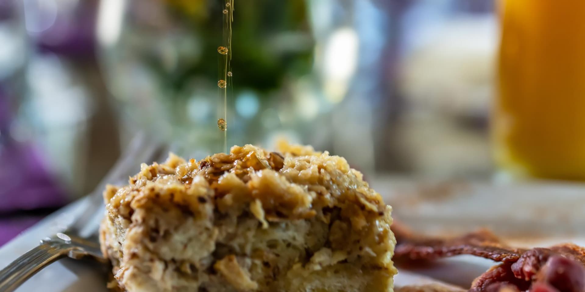 A close-up of a dessert drizzled with syrup, surrounded by bacon on a plate.