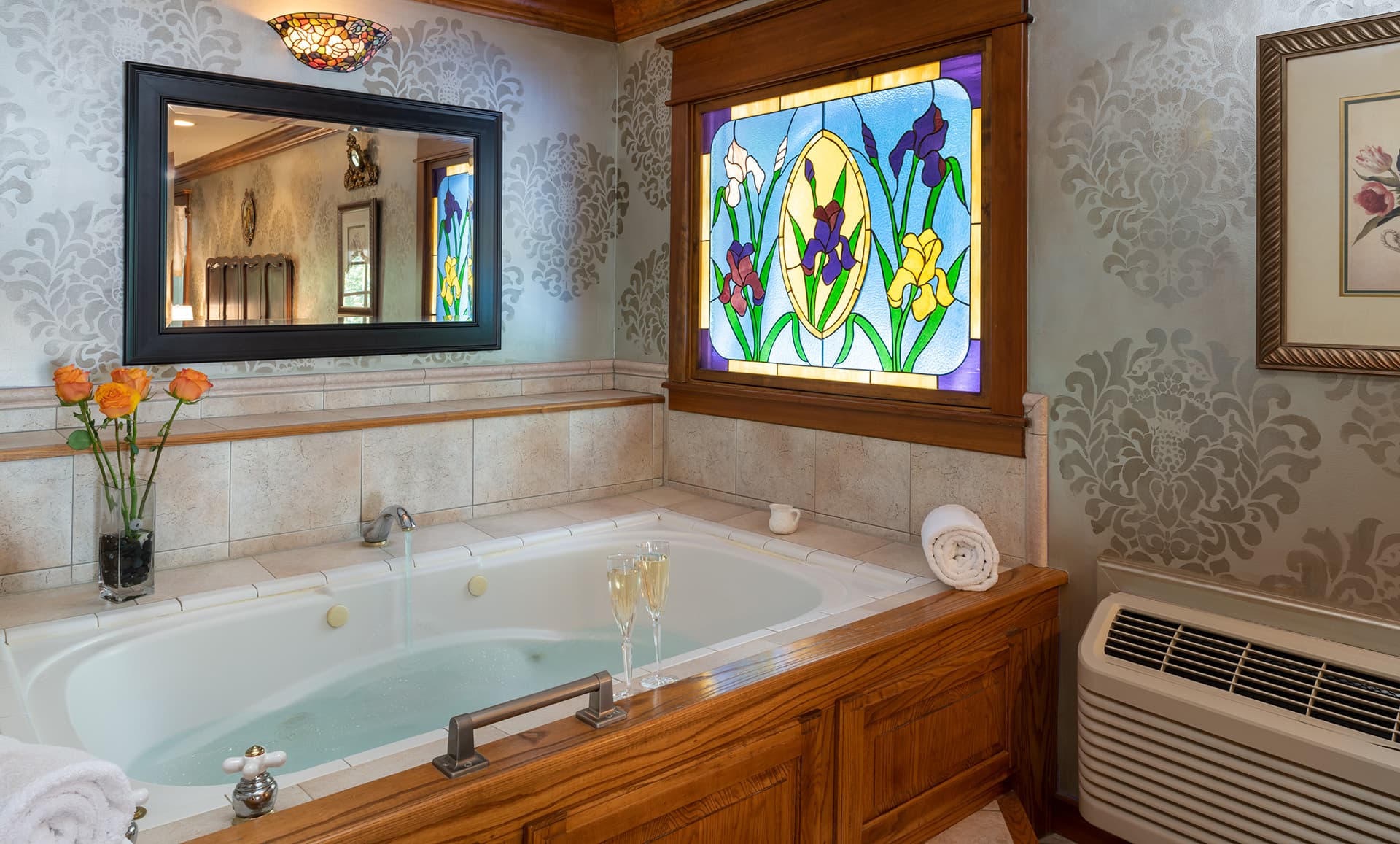 Elegant bathroom featuring a whirlpool tub, stained glass window, and fresh flowers.