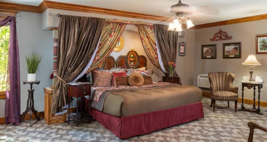 Luxurious bedroom with a large bed, decorative curtains, and elegant furnishings.