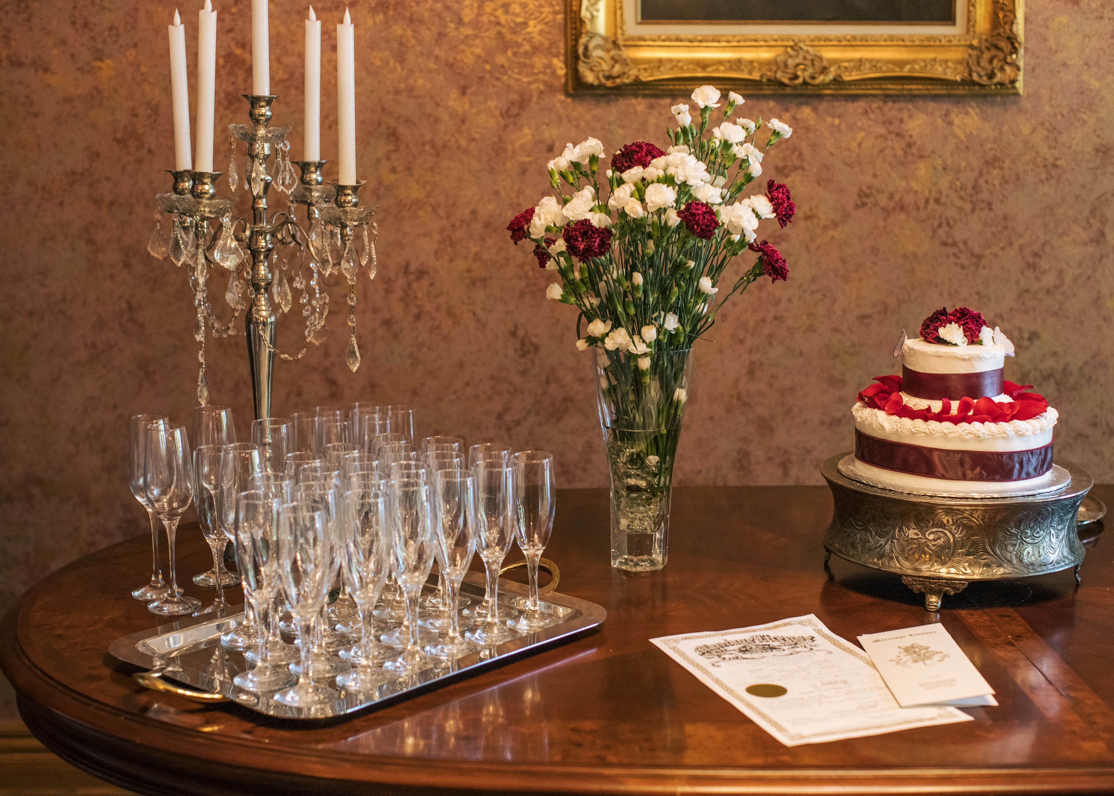 A decorated table with champagne flutes, a floral arrangement, a cake, and a certificate.