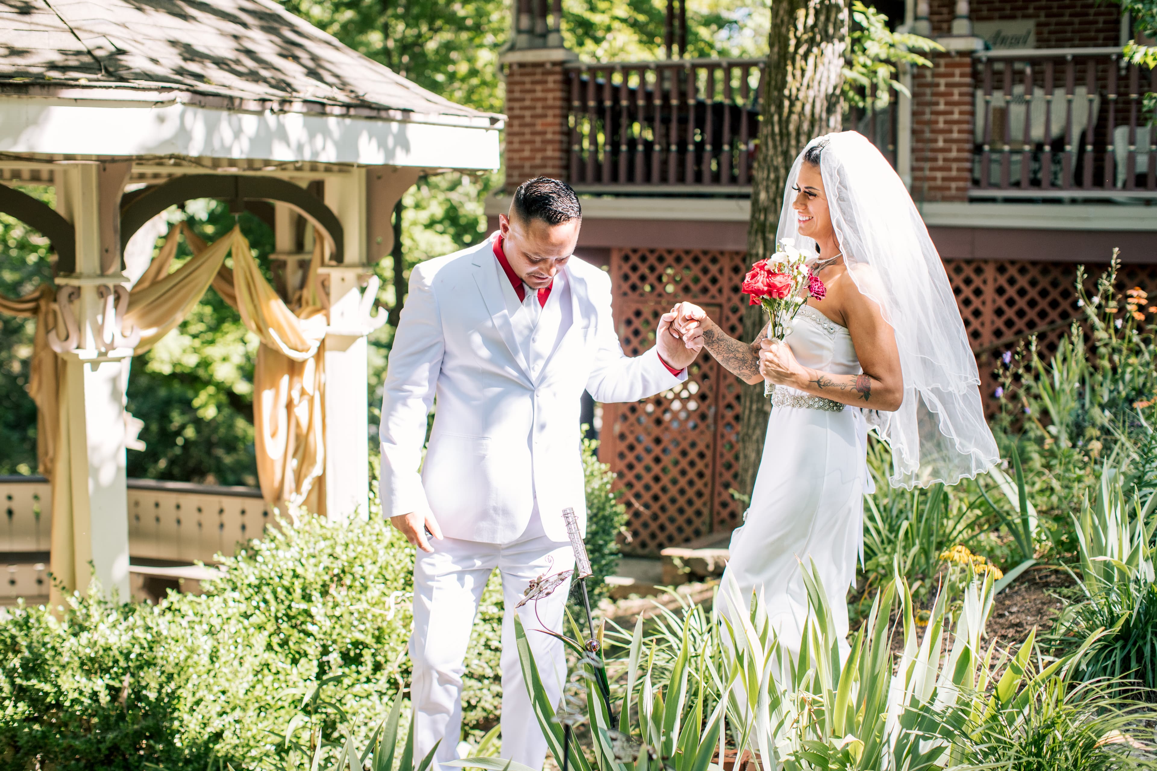 A couple is joyfully engaged in a moment during their outdoor wedding ceremony, surrounded by lush greenery.