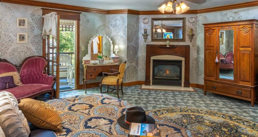 A cozy bedroom featuring elegant furniture, a fireplace, and a balcony view.