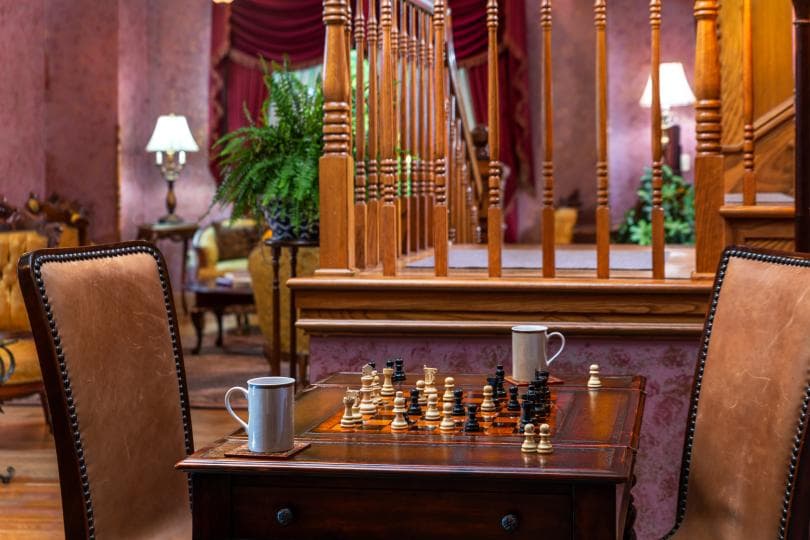 A cozy seating area featuring a chess set on a wooden table, surrounded by elegant decor.